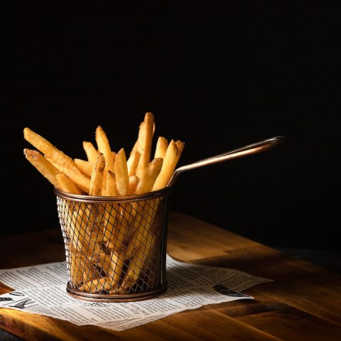a basket of french fries sitting on top of a wooden table