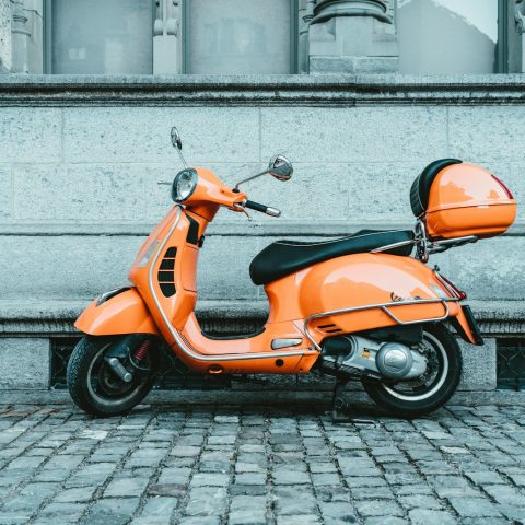 orange and black motor scooter parked on pavement