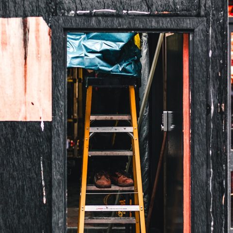 photography of person on A-frame ladder near door