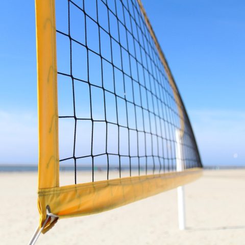Mannen spelen beachvolleybal op een zonnig stadsstrand