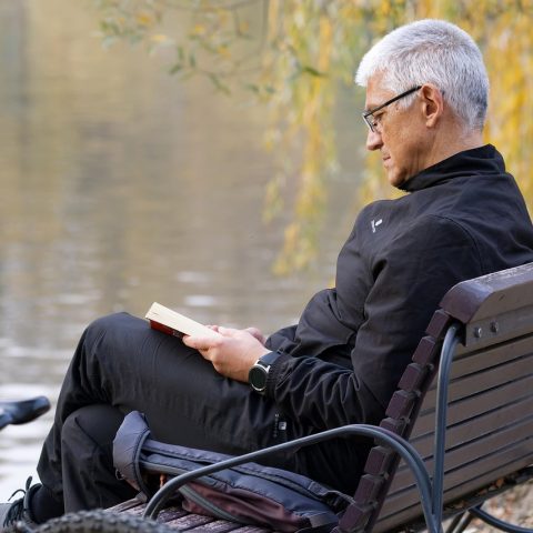 Man die een boek leest buiten in de zomer