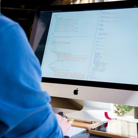 Man met koptelefoon geconcentreerd aan het werk achter zijn bureau