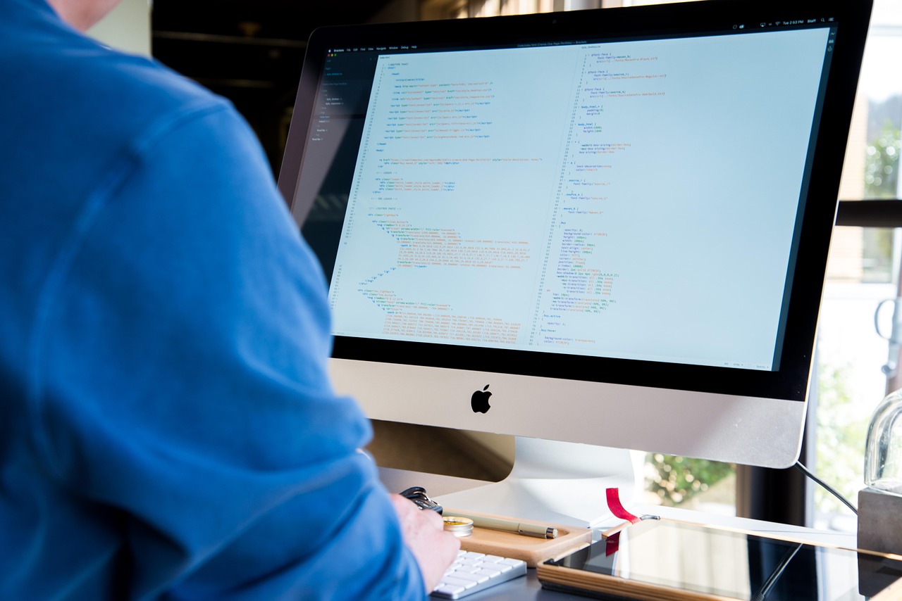 Man met koptelefoon geconcentreerd aan het werk achter zijn bureau