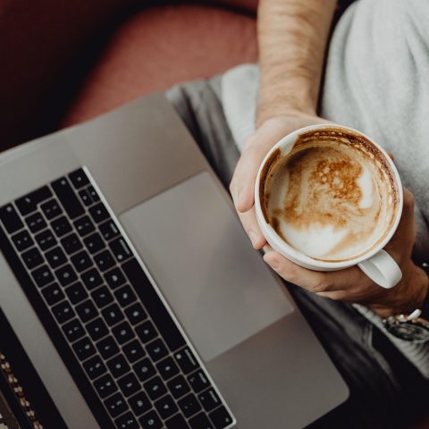Man die serieus werkt op zijn laptop in een thuiskantoor met meerdere schermen