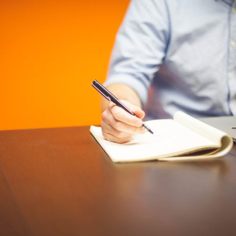 Man die doelen opschrijft in een notitieboek aan een bureau